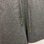 Felpa grigia con cappuccio, cordino e aglet metallico, look casual e confortevole.