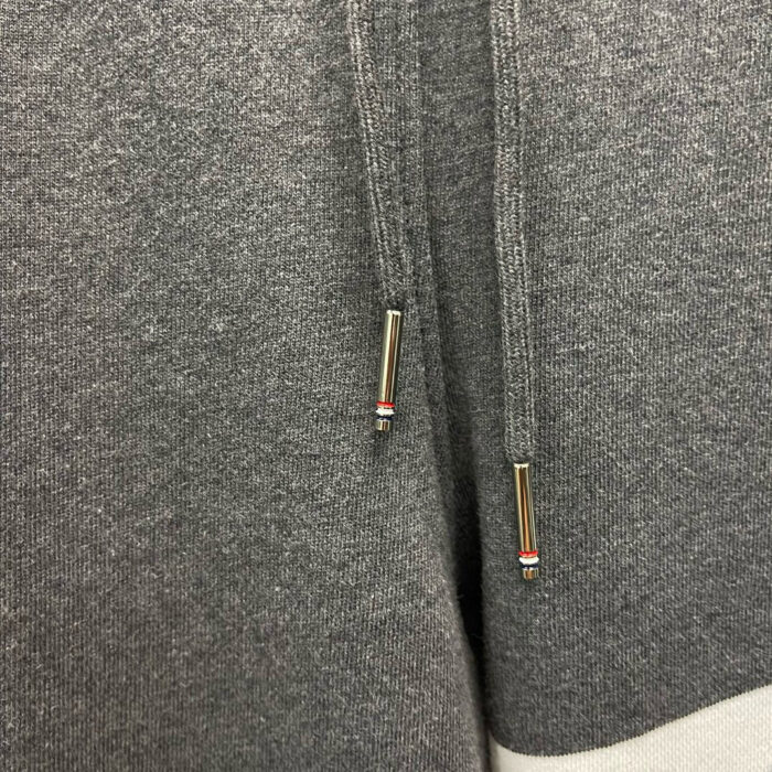 Felpa grigia con cappuccio, cordino e aglet metallico, look casual e confortevole.