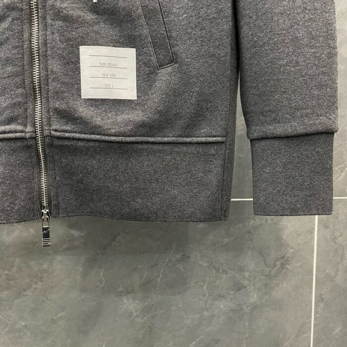 Felpa grigia con tasca zip, dettagli minimalisti, colletto a costina, stile casual moderno.