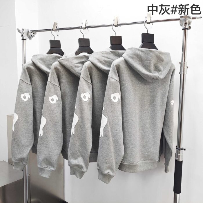 Felpe grigie moderne con grafica sul braccio, stile streetwear, esposte in negozio elegante.