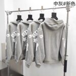 Felpe grigie moderne con logo, streetwear casual e stile minimalista su supporto metallico.