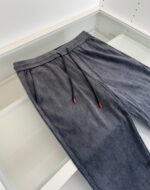 Pantaloni jogger grigi in corduroy con elastico e dettagli rossi, stile casual e confortevole.