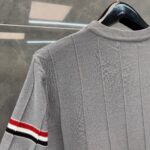 Maglione grigio a costine con dettaglio a strisce sportive rosse, nere e bianche.