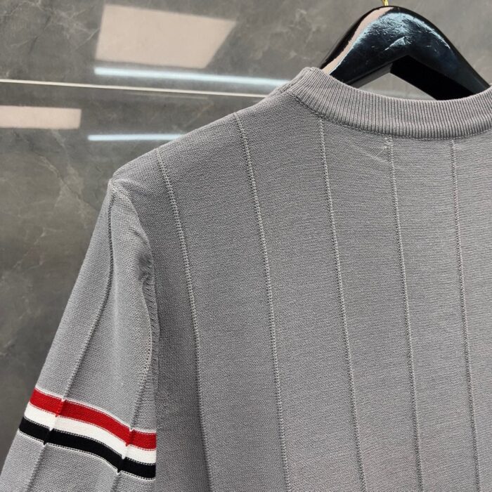 Maglione grigio a costine con dettaglio a strisce sportive rosse, nere e bianche.
