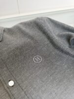Maglietta polo grigia con logo ricamato e bottone, stile casual e sofisticato.