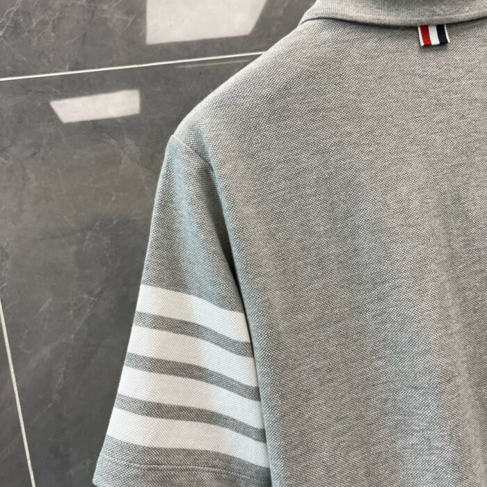 Maglietta polo grigia con Strisce Bianche, tessuto morbido, stile classico e modernità.