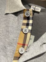 Giacchetto polo grigio con colletto check Burberry e bottoni bianchi, stile elegante e casual.