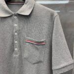 Maglietta polo grigia con tasca a striscia tri-colorata, stile casual elegante, ideale per l’estate.