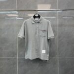 Polo grigia elegante con tasca a contrasto, tessuto morbido e stile versatile.