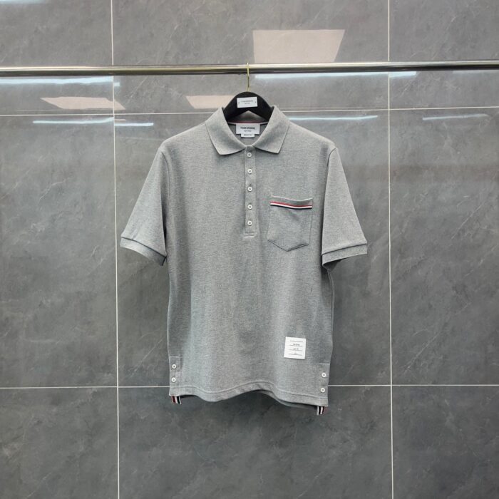Polo grigia elegante con tasca a contrasto, tessuto morbido e stile versatile.