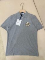Maglietta polo grigia elegante con logo sul petto, colletto classico e dettagli di stile.