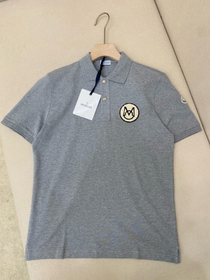 Maglietta polo grigia elegante con logo sul petto, colletto classico e dettagli di stile.