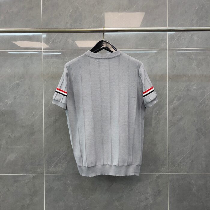 Maglione grigio corto con strisce rosse sulle maniche, stile sportivo e moderno.