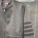 Giacca grigia sporty con collo alta, strisce sulle maniche e interno a righe colorate.