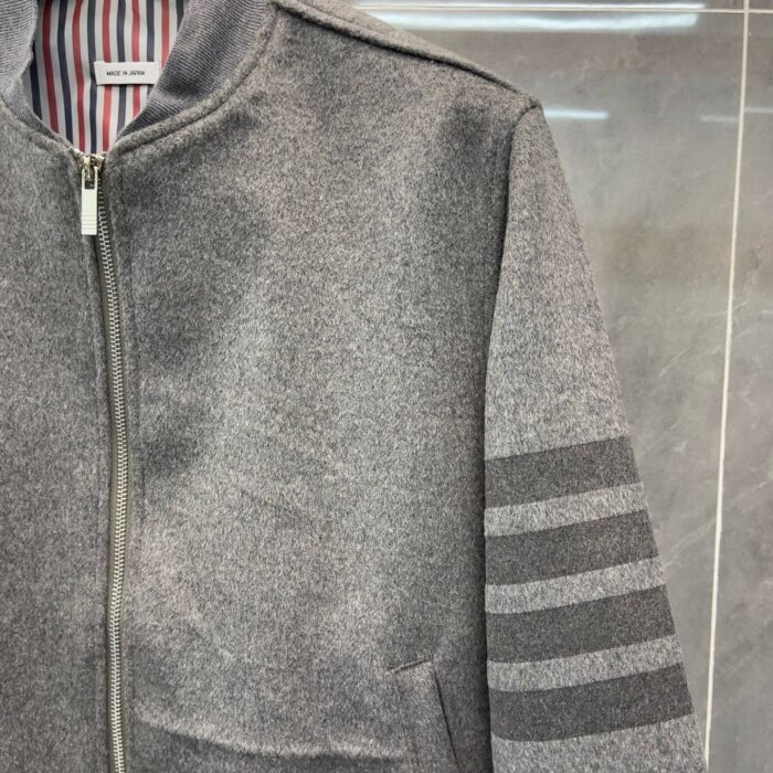 Giacca grigia sporty con collo alta, strisce sulle maniche e interno a righe colorate.