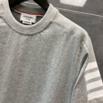 T-shirt grigia sportiva con strisce bianche e logo Tom Brown, stile casual e moderno.