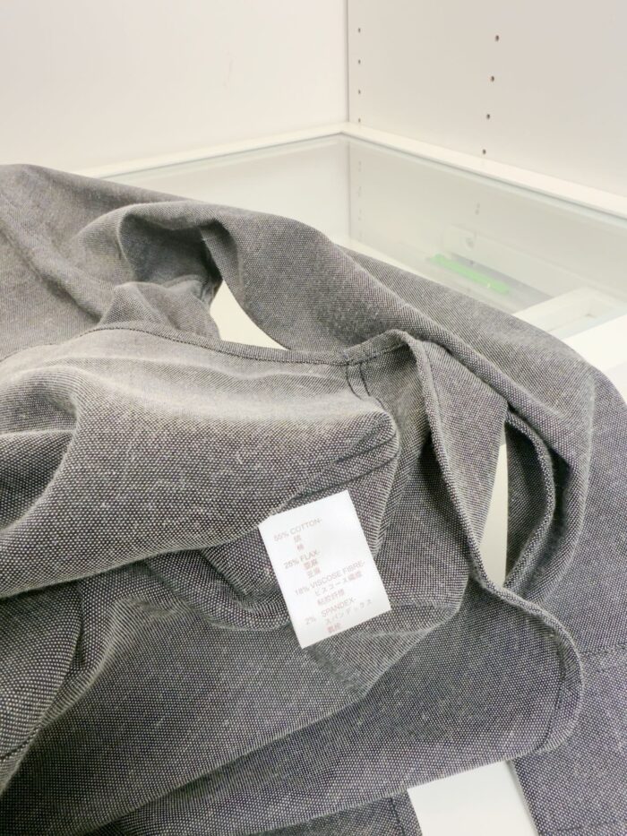 Maglione grigio morbido con etichetta di cura, stile casual e comfort elegante.