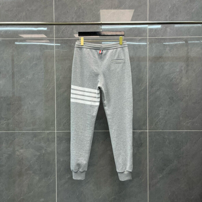 Pantaloni jogger grigi con strisce bianche, stile athleisure, comfort e design moderno.
