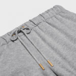 Pantaloni jogger grigi con cintura elasticizzata e cordino con punte in metallo dorato.