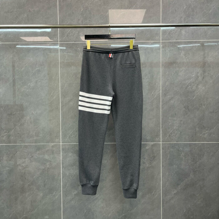 Pantaloni jogger grigi con strisce bianche, comodi, moderni, ideali per sport e relax quotidiano.