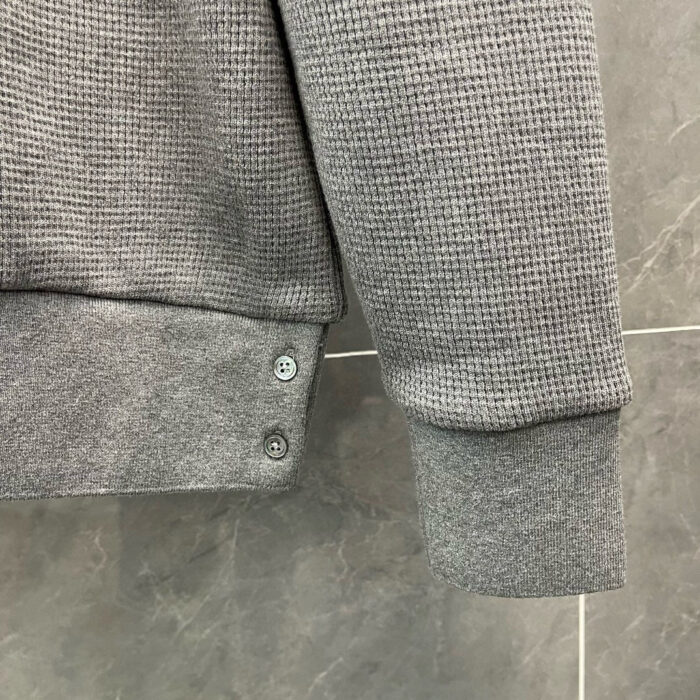 Felpa grigia con polsini a coste e bottoni decorativi, confortevole e versatile.