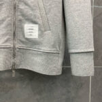 Felpa grigia con tasca e polsini a costine, adatta a look casual e athleisure.