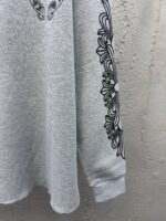 Felpa grigia con stampa floreale nera lunga sul braccio, stile casual e artistico.