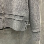 Felpa cinza con zip, dettagli elastici e bottoni decorativi, versatile e confortevole.