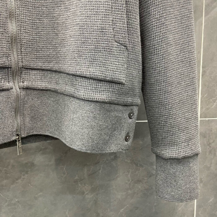 Felpa cinza con zip, dettagli elastici e bottoni decorativi, versatile e confortevole.