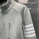 Giacca sportiva grigia con strisce bianche, zip e collo alto, ideale per fitness e casual.
