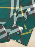 Camicia a quadri verde con polsino e bottone turchese, stile casual e dettagli curati.