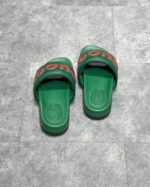 Sandali slip-on verdi con logo rosso, comodi e estivi, su pavimento grigio.