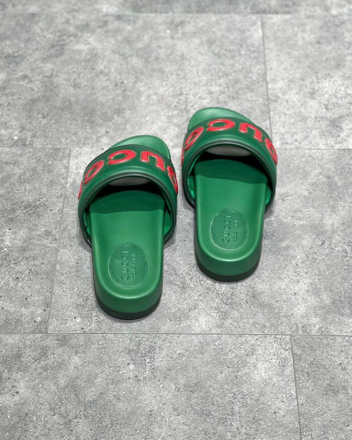 Sandali slip-on verdi con logo rosso, comodi e estivi, su pavimento grigio.