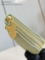 Portafoglio verde elegante con cerniera dorata e charm giocoso, ideale per ogni occasione.