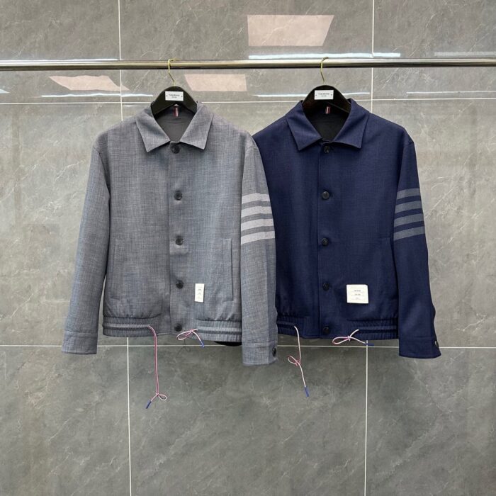 Giacca grigia e navy moderna su esposizione minimalista, stile urbano e dettagli sofisticati.