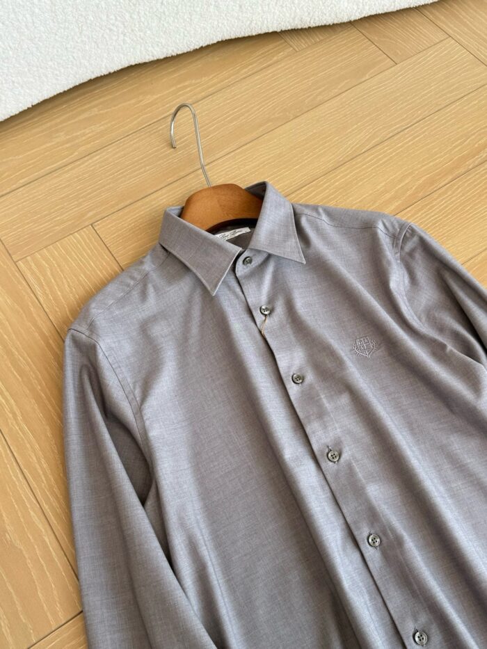 Camicia grigia elegante in tessuto leggero, appesa su stampo di legno, stile raffinato e sobrio