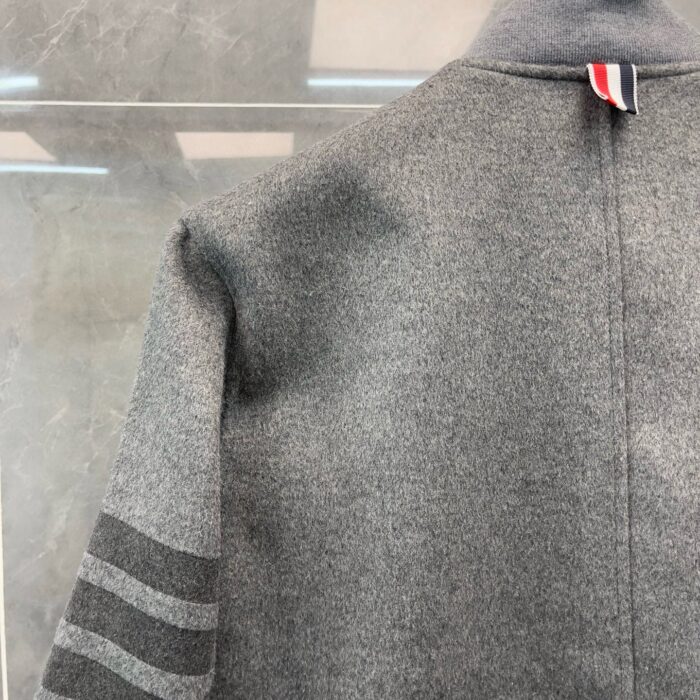 Giacca grigia sportiva con strisce scure e dettagli colorati, stile casual ed elegante.