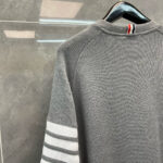 Maglione casual grigio con strisce bianche, dettaglio rosso e design sportivo