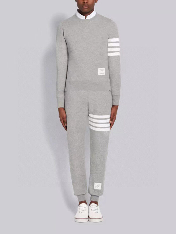 Completo sportivo grigio con strisce bianche, felpa a collo alto e jogger aderenti.