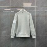 Maglietta grigia sportiva con strisce sulle maniche e colletto alto, stile casual e moderno.
