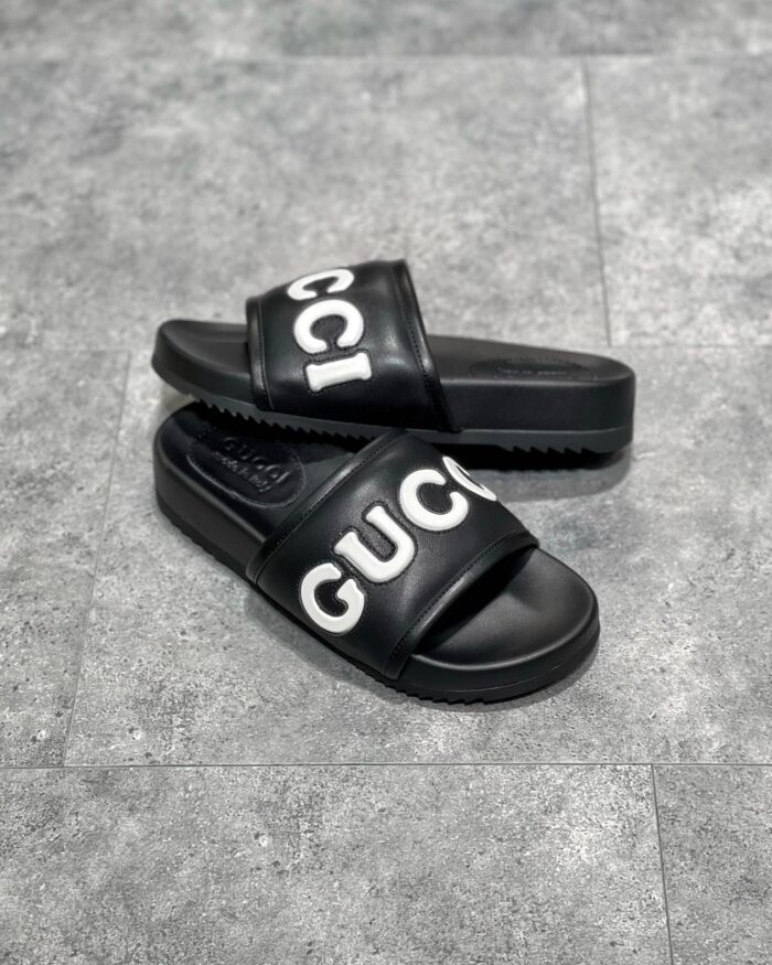 Sandali Gucci neri con logo bianco, stile casual elegante e comfort di lusso.