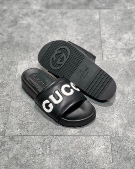 Sandali Gucci neri minimalisti con logo bianco e suola antiscivolo elegante e comoda.
