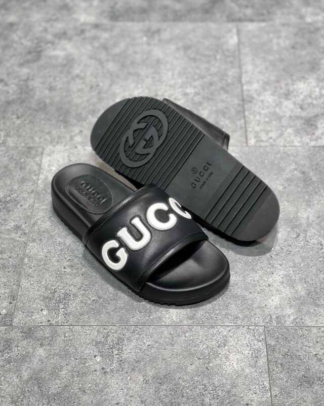 Sandali Gucci neri minimalisti con logo bianco e suola antiscivolo elegante e comoda.