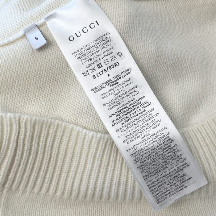 Etichetta Gucci su maglione di lusso, istruzioni di cura incluse.