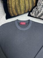 Maglione grigio Gucci stile elegante con cuscini decorativi di lusso e design moderno.