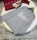 Felpa grigia Gucci con logo in corsivo, stile casual e lusso moderno.