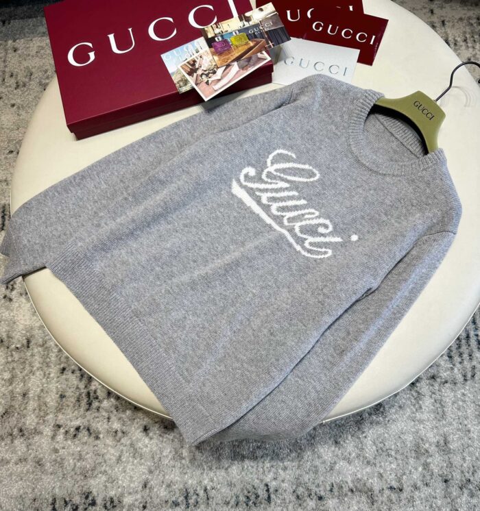 Felpa grigia Gucci con logo in corsivo, stile casual e lusso moderno.