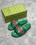 Sandali Gucci verdi con logo rosso e packaging elegante, stile moderno e lusso sofisticato.