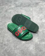 Sandali Gucci verde con logo rosso, stile elegante, comfort e design di lusso femminile.