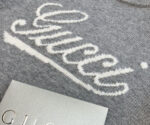 Maglione Gucci grigio con logo elegante, dettagli di lusso e tessuto morbido di alta qualità.
